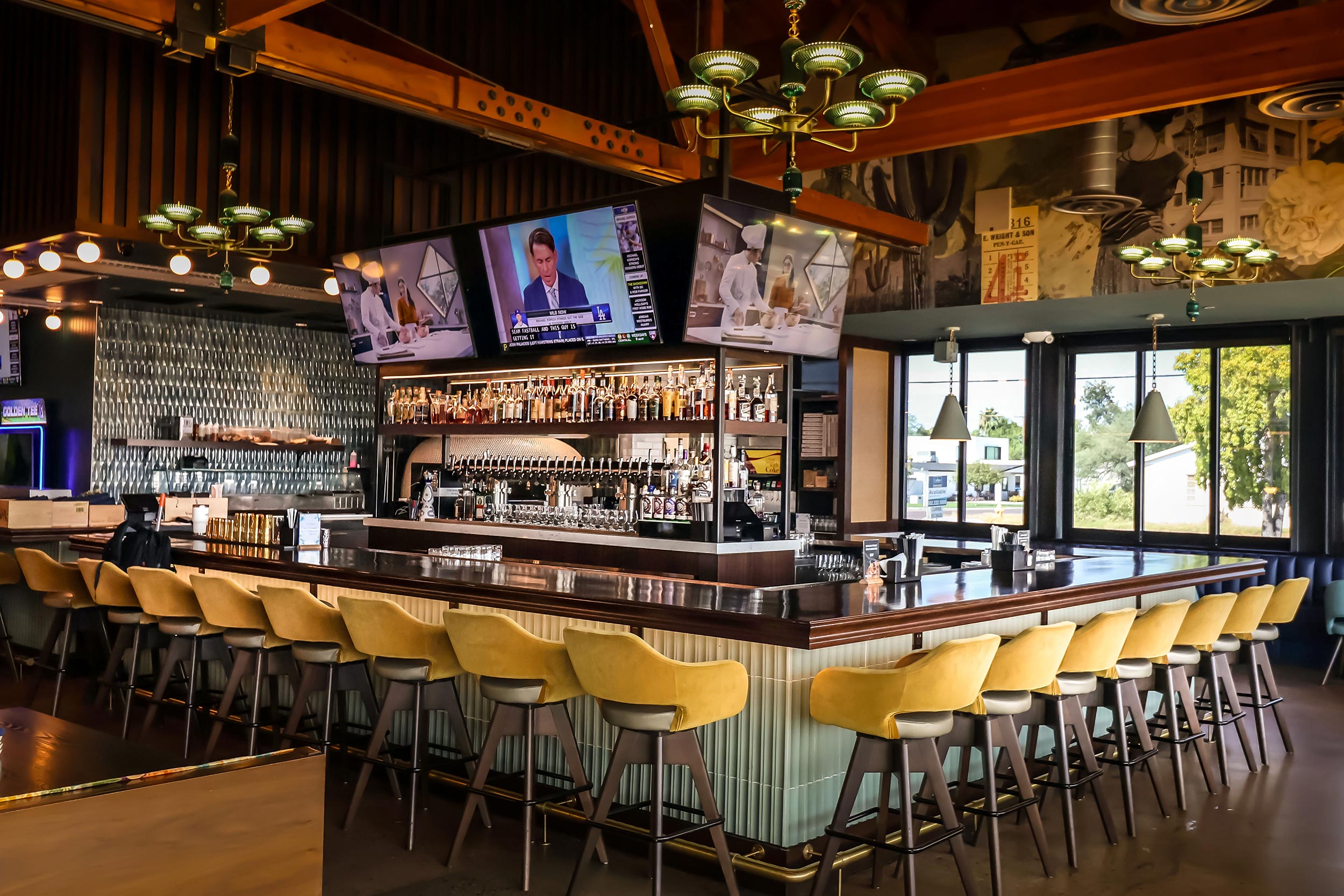 Multiple television screens displaying sports above a crowded bar