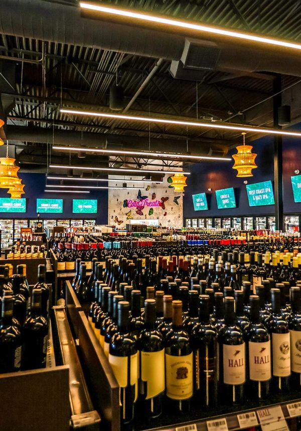 Expansive view of the wine department with hundreds of bottles organized on dark wooden shelving.
