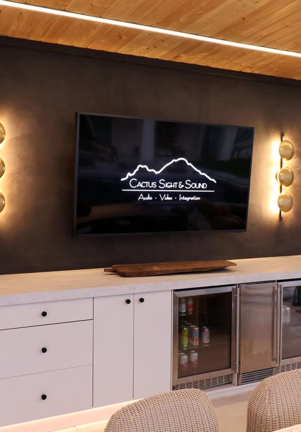 Modern outdoor bar with white drawers and beverage coolers under a television