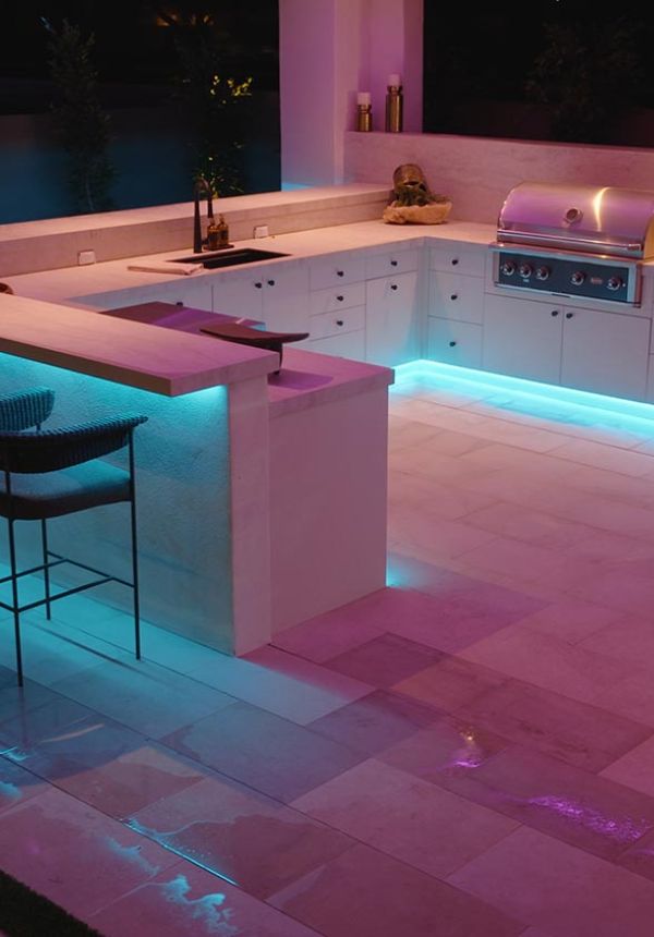 Outdoor bar and grill area with bright teal LED perimeter lighting
